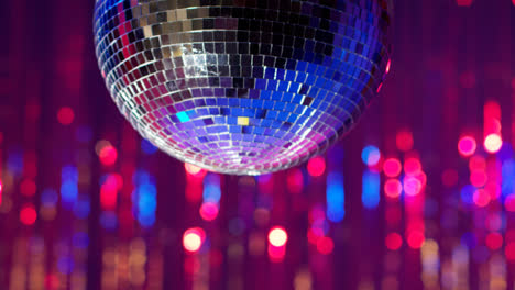 Nahaufnahme-Einer-Spiegelkugel,-Die-Sich-Langsam-In-Einem-Nachtclub-Oder-Einer-Disco-Dreht,-Mit-Funkelnden-Lichtern-Im-Hintergrund